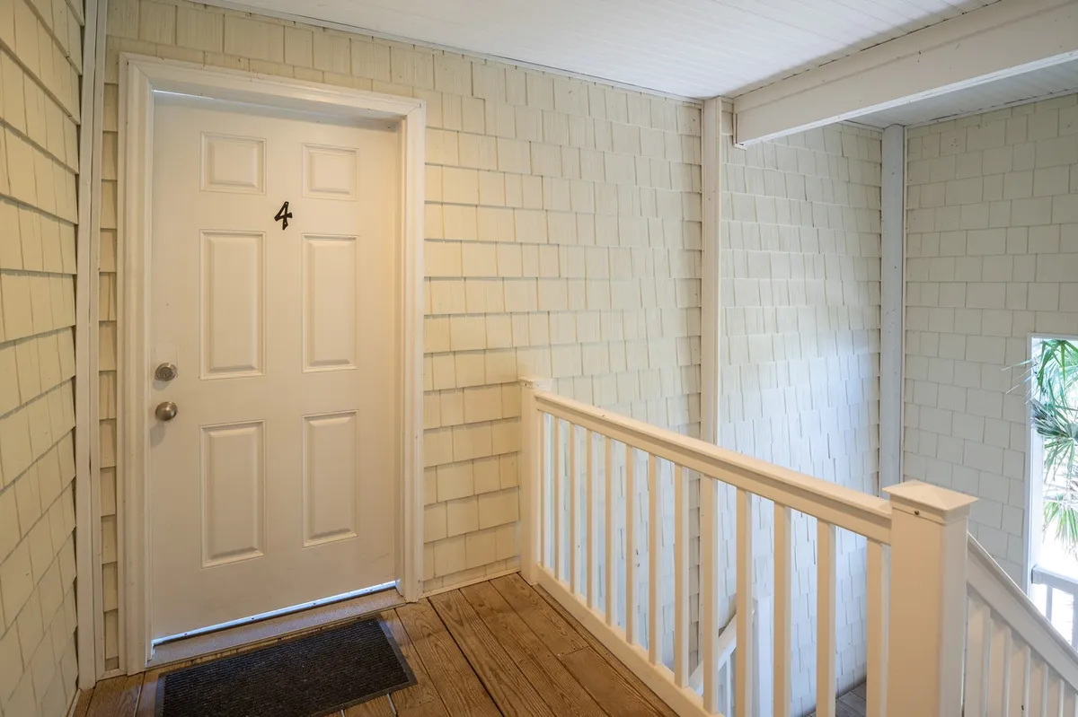A view of the condo's inviting front door, framed by a wooden railing and textured wall. This image suggests a secure, private entry and a welcoming first impression, with subtle cues of comfort and ease for arrivals and departures.